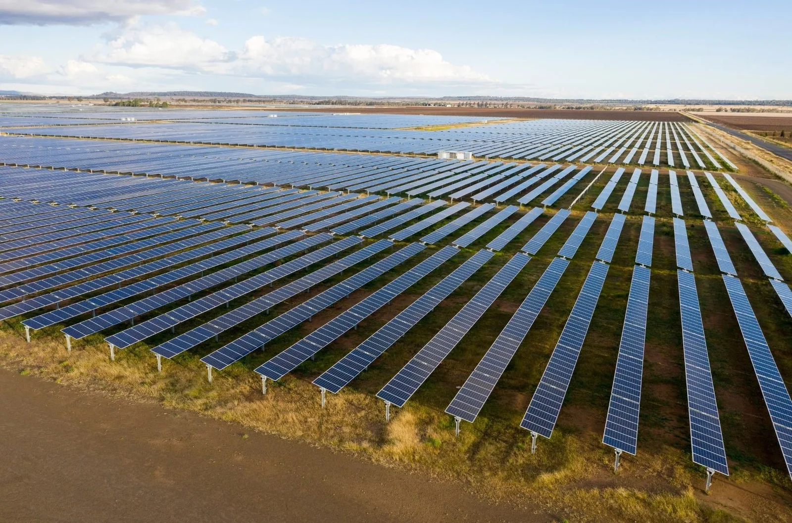 Long rows of photovoltaic panels across a large solar farm